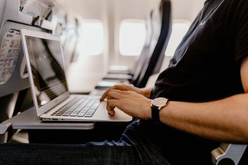 kaboompics_unrecognizable-man-with-notebook-sitting-inside-an-airplane-8013